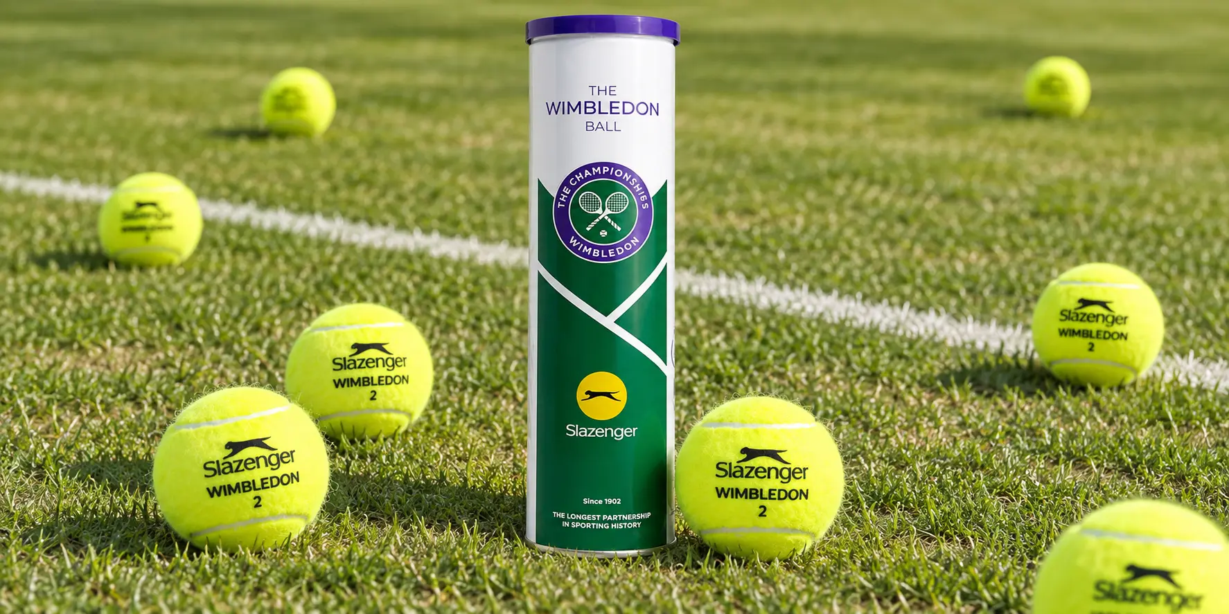Slazenger Wimbledon ball can surrounded by several tennis balls on a natural grass court
