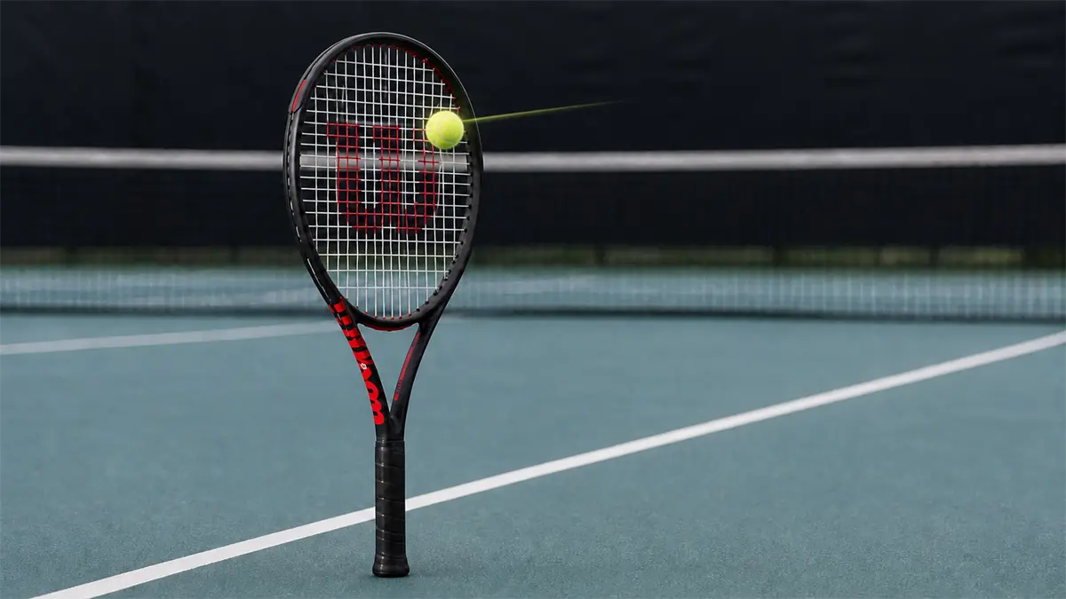 Raqueta Wilson Clash 100 V3 con una pelota impactando suavemente fuera del centro del encordado