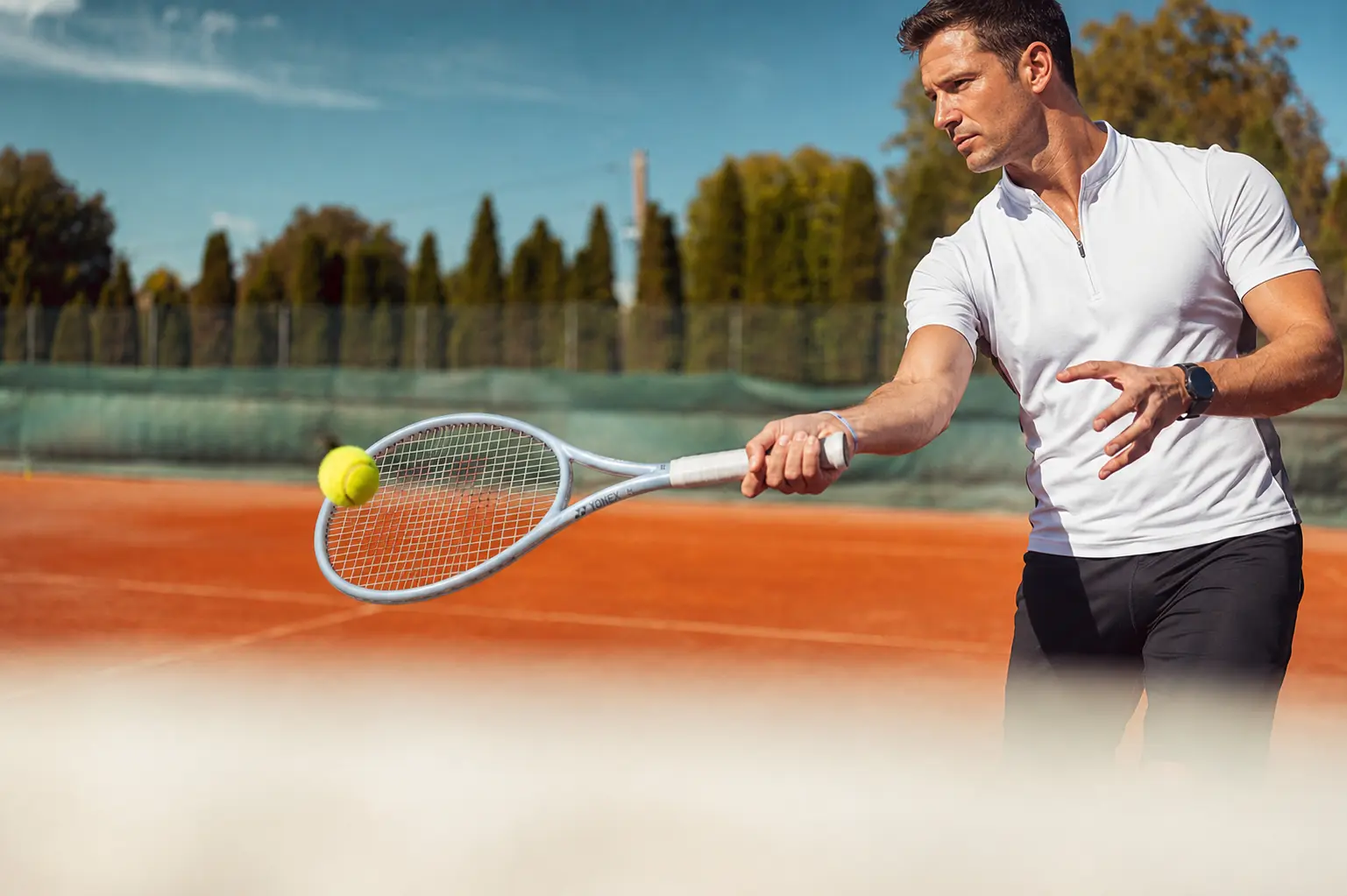 Jugador adulto golpea una volea de derecha con una Yonex MUSE plateada en una pista de club.